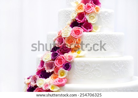 Detail of a white wedding cake decorated with pink sugar flowers
