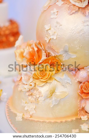 Fancy delicious white and yellow wedding cake decorated with flowers and butterflies