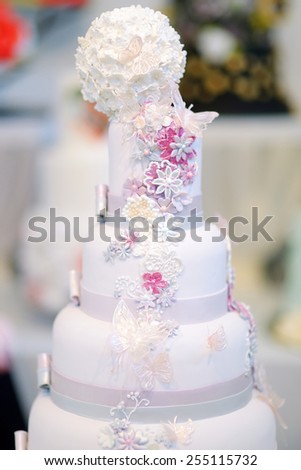 Fancy delicious white wedding cake decorated with flowers and butterflies