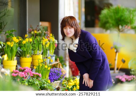 Beautiful young woman selecting flowers at flower market in Paris, France