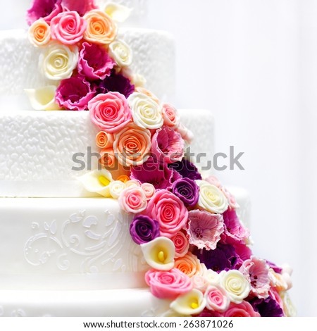 Detail of a white wedding cake decorated with pink sugar flowers