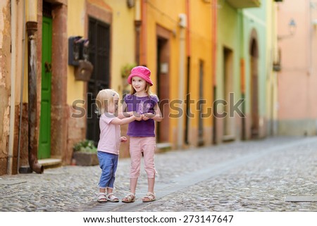 Two cute little sisters having fun outdoors on beautiful sunny day in italian town