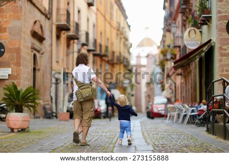 Two little sisters and their father on a street of typical italian town