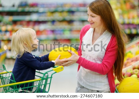 Mother and daughter choosing a melon in a fruit store
