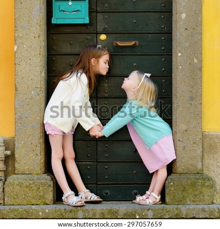 Two adorable little sisters having fun together on warm and sunny summer day in italian town