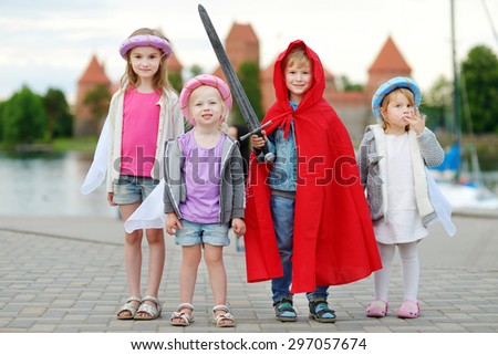 Four kids in princesses and a knight costumes having fun outdoors