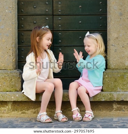 Two adorable little sisters having fun together on warm and sunny summer day in italian town