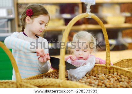 Cute little sisters buying hazelnuts in a food store or a supermarket