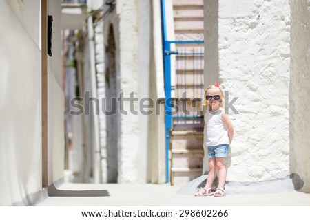 Adorable little girl on warm and sunny summer day in typical italian town