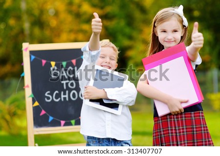 Two adorable little schoolkids feeling very exited about going back to school