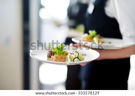 Waiter carrying plates with meat dish on some festive event, party or wedding reception