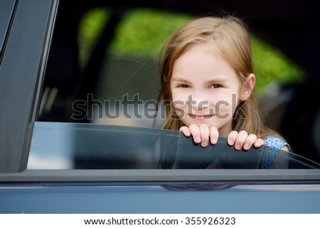 A little girl is sticking her head out the car window looking forward for a roadtrip or travel