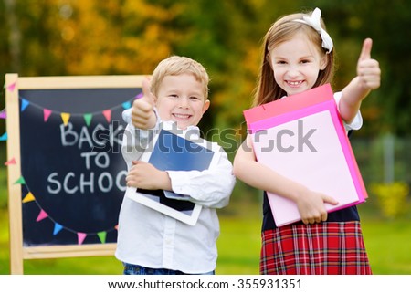 Two adorable little schoolkids feeling very exited about going back to school