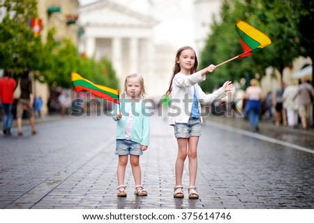 Two adorable little sisters holding Lithuanian flags in Vilnius, the capital of Lithuania