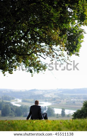 Business man resting under an giant oak