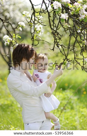 Young mother and her daughter in blossoming trees