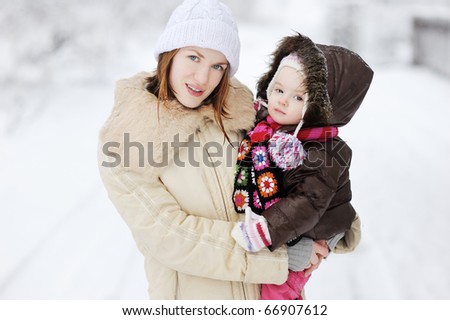 Toddler girl and her mother on beautiful snowy winter day