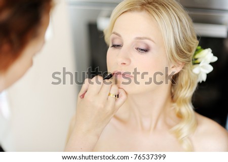 Young beautiful bride applying wedding make-up by make-up artist Young beautiful bride applying wedding make-up by make-up artist