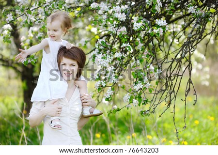 Young mother and her daughter in blossoming apple trees