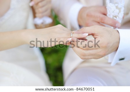 Groom putting a wedding ring on bride\'s finger
