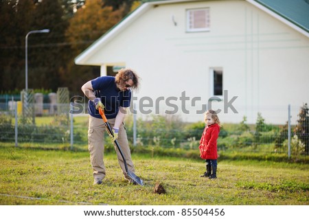 A man shovels a hole in the yard, preparing to plant a tree