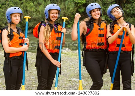 Group of four young ladies prepared to go white water rafting, wearing specific equipment