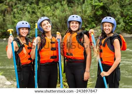 Group of four young ladies prepared to go white water rafting, wearing specific equipment