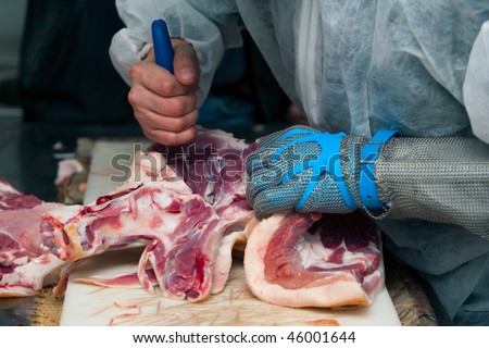butcher that cuts fresh pork wearing protective gloves