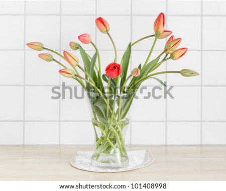 Flower vase with red tulips in a kitchen.
