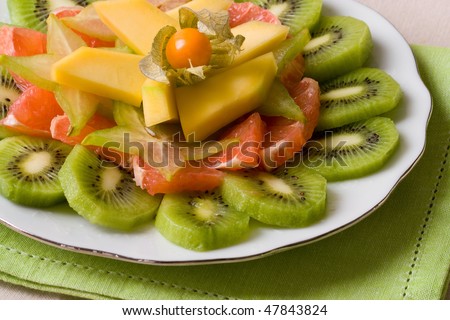 Selective focus image of a tropical fruit salad made from grapefruits, mango, physalis and kiwi fruits.