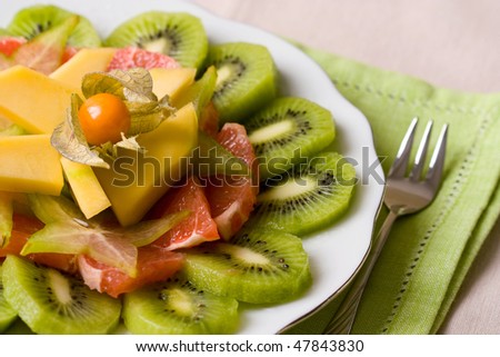 Selective focus image of a tropical fruit salad made from grapefruits, mango, physalis and kiwi fruits.