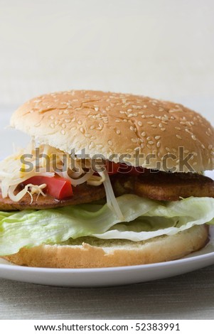 Close-up of an Asian fast food burger made from sprouts, red bell pepper, marinated tofu and iceberg lettuce with seame bread.
