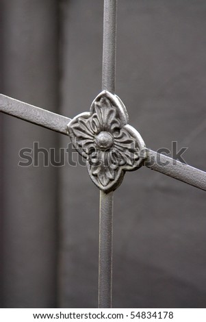 Selective focus image of a wrought ironwork showing a decorative flower which belongs to a gate.
