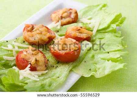 Tomatoes grilled with parmesan cheese and pignolias, served as starter on iceberg lettuce.