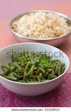 Bowls with green beans and rice which are cooked in Indian style.