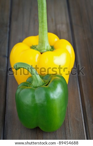 Green and yellow sweet pepper on a wooden background.