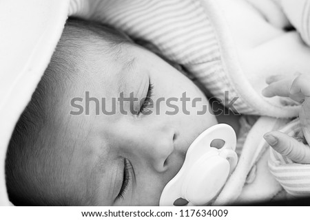 Closeup of a sleeping new born little baby. Shot in black and white, slight grain on photo