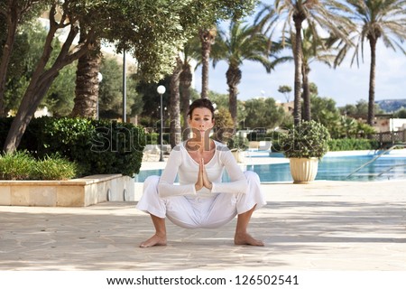 Photo of a middle aged lady doing a yoga pose in a beautiful hotel garden