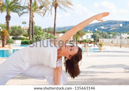 Middle aged woman doing warrior yoga pose with eyes clothes