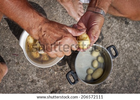 A man peeling early potatoes with a knife outdoors in Sweden, Scandinavia