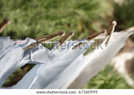 Beautiful children\'s clothes pegged up with old fashioned wooden pegs drying outside. Soft focus, sharpness on pegs