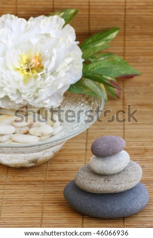 pebbles, flower and bowl with water and white pebbles on bamboo mat
