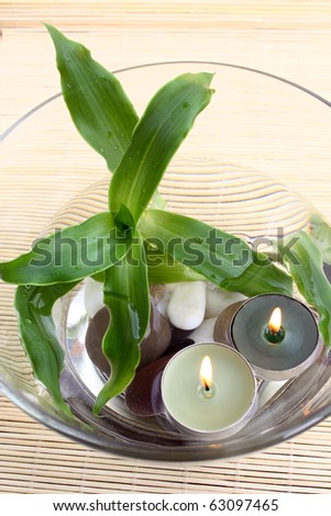 spa decoration: top view of bowl with water, pebbles, plant and burning candles