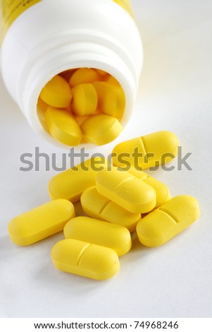 close-up yellow pills spilled from bottle