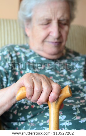 asleep old woman holding wooden cane while having a happy dream