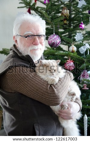 senior man and his cat in front of noel tree in living room