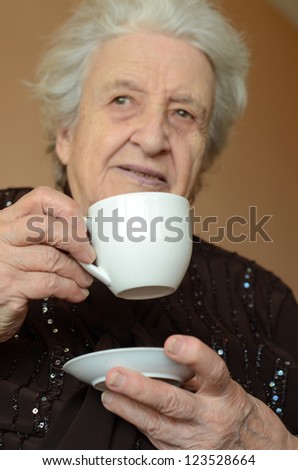 senior woman holding a cup of coffee in order to drink