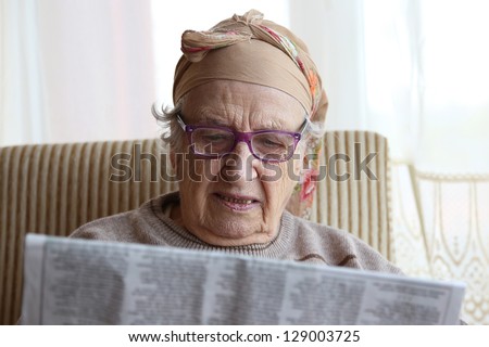 senior woman wearing eyeglasses while reading a newspaper