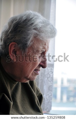 senior woman looking out behind the window