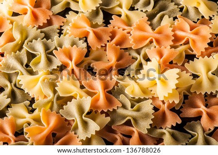 Multi colored raw pasta in the form of bows as a background